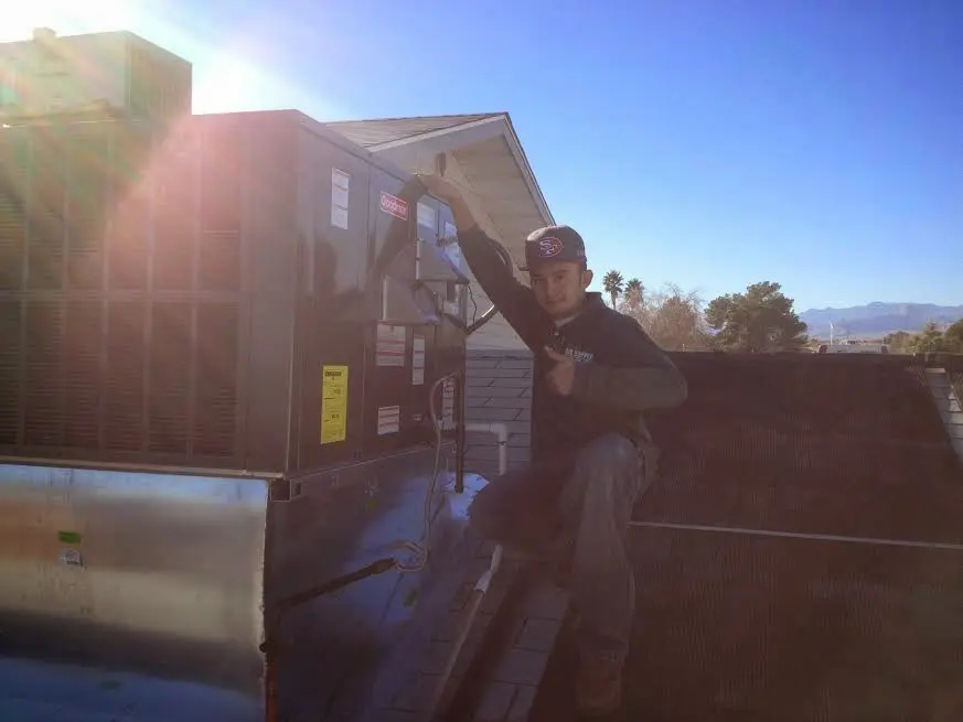 HVAC technician performing AC Tune-Up on a rooftop unit in Bellevue